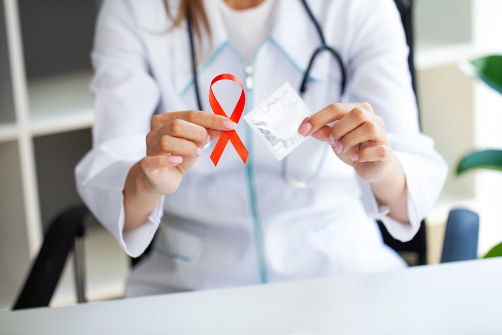 Médica segurando laço vermelho, símbolo do Dezembro Vermelho